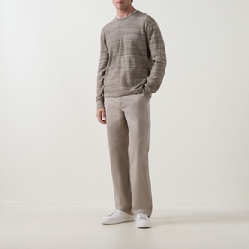 Model wearing Calvin Klein Jeans 90S Straight-Leg Chinos in Vintage Khaki, styled with a striped knit sweater and white trainers.