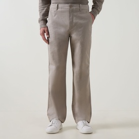 Model wearing Calvin Klein Jeans 90S Straight-Leg Chinos in Vintage Khaki, mid-rise with belt loops, styled with white trainers and a grey knit top.
