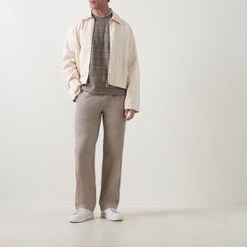 Model wearing Calvin Klein Jeans 90S Straight-Leg Chinos in Vintage Khaki with cream jacket, grey top and white trainers