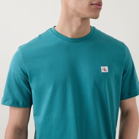 Model wearing Calvin Klein Jeans Logo Badge 30s Classic T-Shirt in North Sea, showing embroidered logo badge detail at chest, crew neck, short