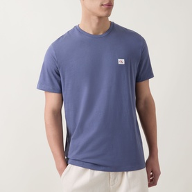 Model wearing Calvin Klein Jeans Logo Badge 30s Classic T-Shirt in Blue Nomad, crew neck, short sleeves, small logo badge at chest, styled with cream