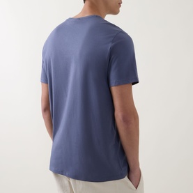 Model wearing Calvin Klein Jeans Logo Badge 30s Classic T-Shirt in Blue Nomad, rear view showing crew neck and short sleeves.