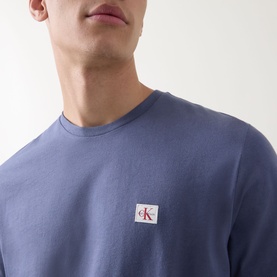 Model wearing Calvin Klein Jeans Logo Badge 30s Classic T-Shirt in Blue Nomad, crew neck with small woven logo badge at chest.