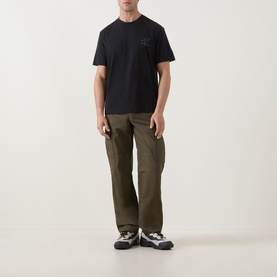Model wearing Calvin Klein Jeans Monogram Logo T-Shirt in black with olive cargo trousers and grey trail trainers.