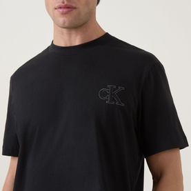 Model wearing Calvin Klein Jeans Monogram Logo T-Shirt in black, featuring tonal CK chest logo embroidery and crew neck.