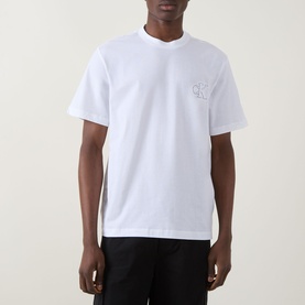 Model wearing Calvin Klein Jeans Monogram Logo T-Shirt in Bright White, crew neck, short sleeves, with black trousers.