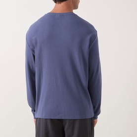 Model wearing Calvin Klein Jeans Waffle Knit Logo T-Shirt in Blue Nomad, long sleeves, ribbed cuffs, back view, styled with dark trousers