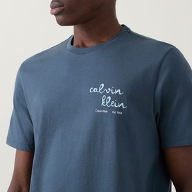 Model wearing Calvin Klein Jeans Travel Line Logo T-Shirt in Dark Slate, crew neck with cursive logo print to chest