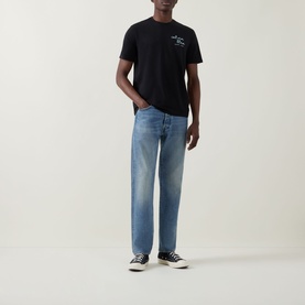 Model wearing Calvin Klein Jeans Travel Line Logo T-Shirt in black with light blue straight-leg jeans and black high-top trainers.