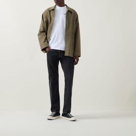 Model wearing Calvin Klein Jeans Travel Line Logo T-Shirt in Bright White, styled with olive jacket and dark jeans.