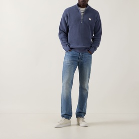 Model wearing Calvin Klein Jeans Waffle-Knit Logo Half-Zip Sweatshirt in Blue Nomad with light-wash jeans and white trainers.