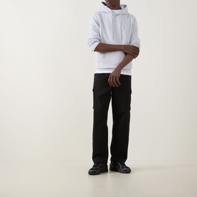 Model wearing Calvin Klein Jeans Monogram Badge Drawstring Hoodie in Marble Grey with black cargo trousers and black leather shoes.
