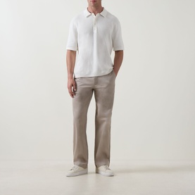 Model wearing Calvin Klein Jeans Waffle-Knit Logo Polo Shirt in Tofu with four-button placket, styled with taupe trousers and white trainers.