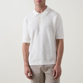 Model wearing Calvin Klein Jeans Waffle-Knit Logo Polo Shirt in Tofu, with polo collar and short sleeves, styled with stone trousers.