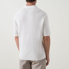 Model wearing Calvin Klein Jeans Waffle-Knit Logo Polo Shirt in Tofu, back view, styled with light beige trousers.
