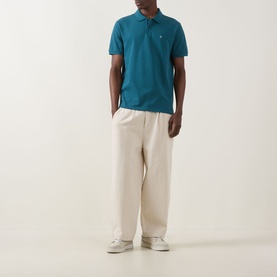 Model wearing Calvin Klein Jeans Tahoe Green Regular Polo with cream wide-leg trousers and white trainers
