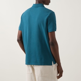 Model wearing Calvin Klein Jeans Tahoe Green Regular Polo, short sleeves, rear view, styled with cream trousers.
