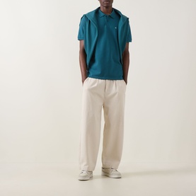 Model wearing Calvin Klein Jeans Tahoe Green Regular Polo with cream wide-leg trousers and white trainers.