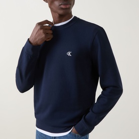 Model wearing Calvin Klein Jeans Monogram Logo Sweatshirt in black, crew neck with ribbed trims and embroidered monogram logo, styled with white tee