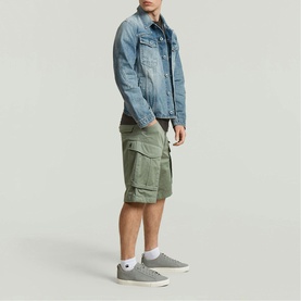 Model wearing G-Star shorts in LT ORPHUS green with cargo pockets, styled with a light blue denim jacket and grey trainers.