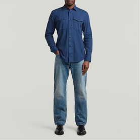 Model wearing G-Star Slim Shirt in Rank Blue GD, long-sleeved with chest pockets, styled with light-wash straight-leg jeans.