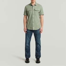 Model wearing G-Star Slim Shirt in light sage green with twin chest pockets, styled with dark blue jeans and black boots
