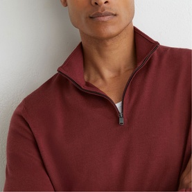 Model wearing Reiss rooibos red quarter-zip sweatshirt, close-up showing zip collar detail and fine knit texture.