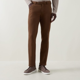 Model wearing Meyer brown cotton-elastane slim-fit trousers, styled with a grey knit and grey slip-on shoes
