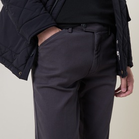 Model wearing Meyer grey cotton-elastane trousers with belt loops, styled with a black quilted jacket.