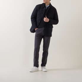 Model wearing Meyer grey cotton-elastane trousers, styled with a navy quilted jacket and white trainers
