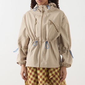 Model wearing Damson Madder Matilda Waterproof Gingham Raincoat in brown check with fixed hood and blue toggle details, styled with check wide-leg