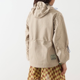 Model wearing Damson Madder Matilda Waterproof Gingham Raincoat in brown check with fixed hood, elasticated cuffs and logo badge, styled with yellow