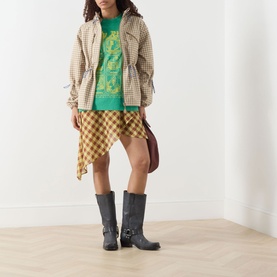 Model wearing Damson Madder Matilda Waterproof Brown Gingham Raincoat with checked skirt, green top and grey western boots