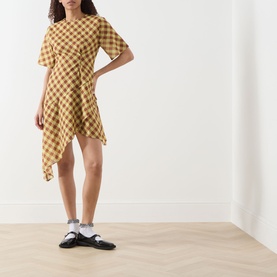 Model wearing Damson Madder Harmony Gingham Mini Dress in multi yellow check, asymmetric hem, short sleeves, styled with black mary jane shoes