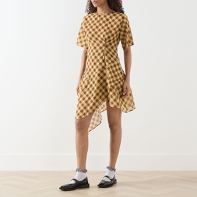 Model wearing Damson Madder Harmony Gingham Mini Dress in multi-coloured check with asymmetric ruffle hem, styled with black loafers and white socks.