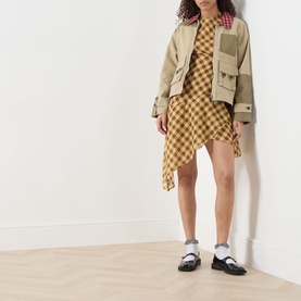 Model wearing Damson Madder Harmony Gingham Mini Dress in multi, asymmetric hem, styled with a patchwork jacket and black loafers