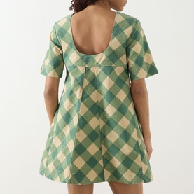 Model wearing Damson Madder Bridget Reversible Mini Dress in green gingham, showing open back with buttoned tab detail, short sleeves, A-line