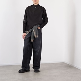Model wearing Pellador Logo Football Training Sweatshirt in black with mock neck, styled with wide-leg dark trousers and black chunky shoes.