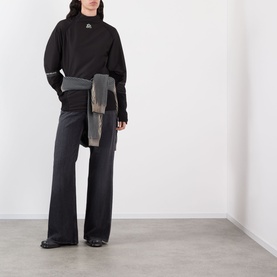 Model wearing Pellador Logo Football Training Sweatshirt in black with mock neck, styled with wide-leg black trousers and a wrapped grey jacket at