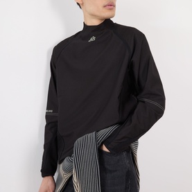 Model wearing Pellador Logo Football Training Sweatshirt in black with mock neck, raglan sleeves and logo detail, styled with striped trousers.