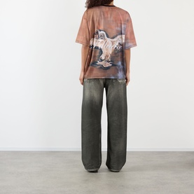 Model wearing Pellador Swan Graphic T-Shirt in print, shown from back, styled with wide-leg grey washed jeans.