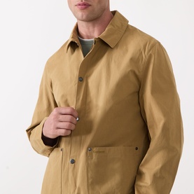 Model wearing Barbour Bayfield Logo Overshirt in camel, showing point collar and snap button placket, styled over a green crew-neck top.