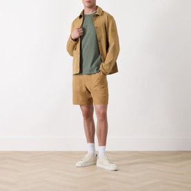 Model wearing Barbour Bayfield Logo Overshirt in Camel with matching shorts, olive T-shirt, and white trainers.