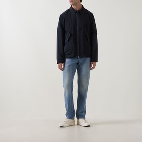 Model wearing Barbour dark navy casual jacket with chest pockets, styled with light wash jeans and cream trainers