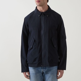 Model wearing Barbour dark navy casual jacket with zip front, spread collar, and flap pockets, styled with light blue jeans.