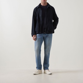 Model wearing Barbour Dark Navy casual jacket with zip fastening, styled with light blue jeans and white trainers.