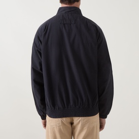 Model wearing Barbour navy cotton casual jacket, rear view, with elasticated hem and cuffs, styled with beige trousers