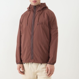 Model wearing Barbour Re-Engineered Flyweight Showerproof Jacket in Pepper brown, hooded with two-way zip, styled with cream trousers.