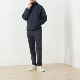 Model wearing Barbour navy casual jacket with funnel neck, styled with grey trousers and white trainers