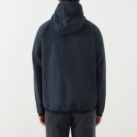Model wearing Barbour navy casual jacket, rear view showing hood and elasticated hem, paired with grey trousers